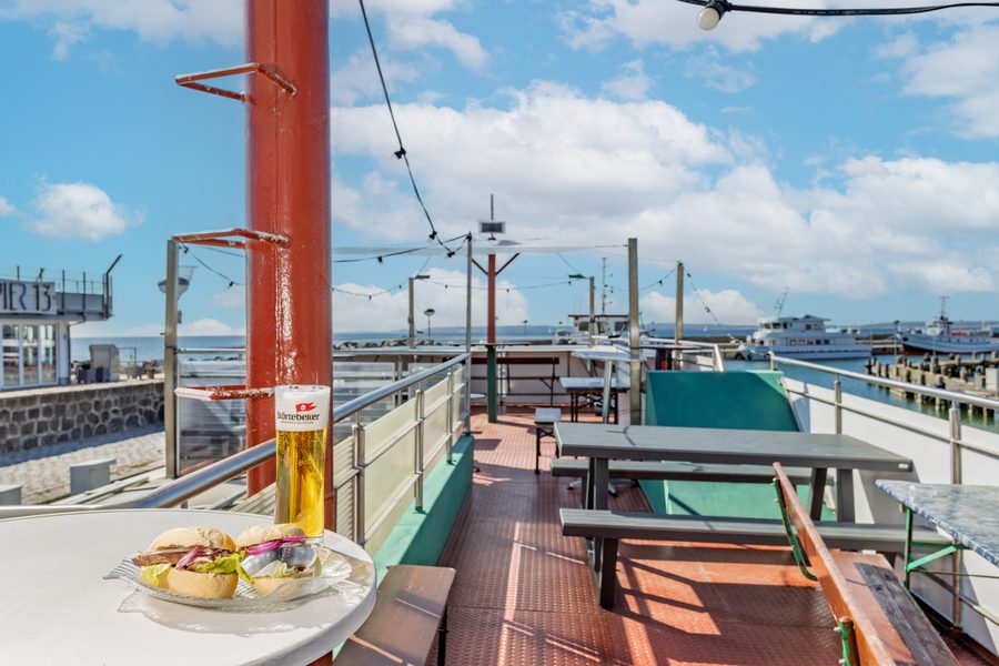 Sonnendeck mit Tischen und Hafen-Lichterkette